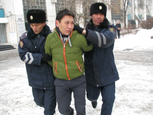A protestor is bundled away by the police in Almaty